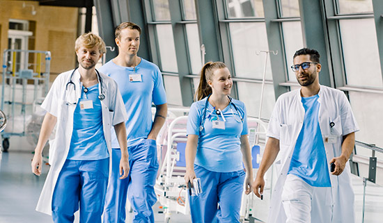 Fire yngre læger går ned ad en hospitalsgang