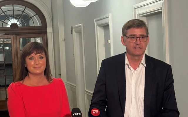 Sophie Løhde og Jørgen Skadborg ved doorsteppressemøde foran bord og ser mod den fremmødte presse og taler