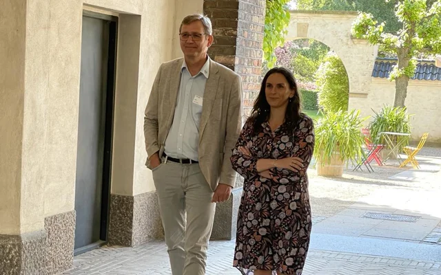 Moderaternes formand, Monika Rubin, smiler i kjole og sandaler står udenfor sammen med PLO's formand, Jørgen Skadborg, i beige jakkesæt med lyseblå skjorte og briller