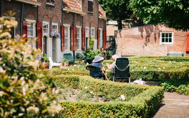 To ældre mennesker der sidder udenfor i solskin og snakker