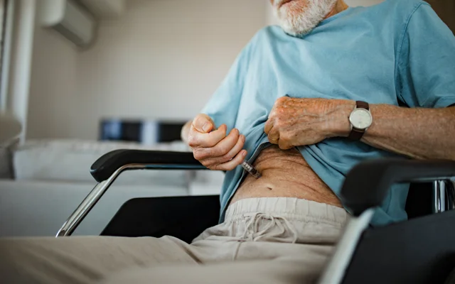 Ældre hvid mand med skæg stikker sig i maven med medicin