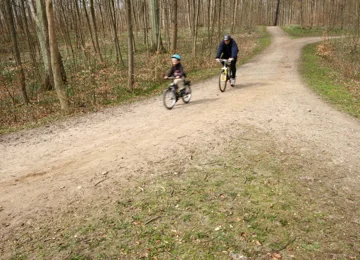 Far og søn cykler i skoven.