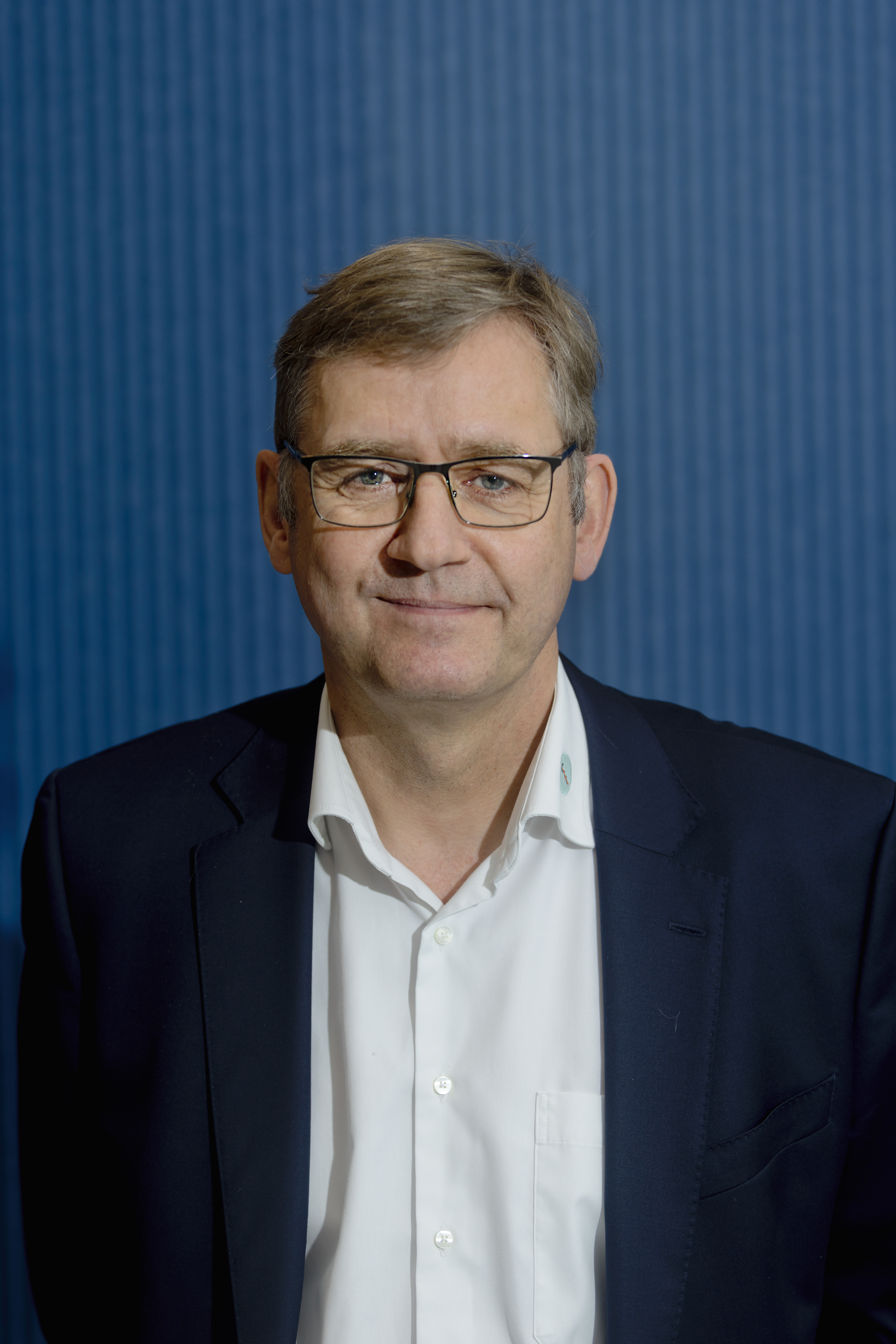 Forman Jørgen Skadborg står foran en blå væg og ser ind i kameraet