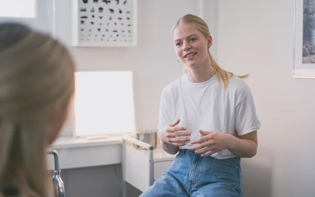 Ung læge taler med patient i konsultation almen praksis