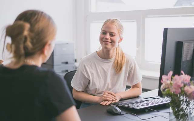 Ung kvinde taler med person, der ligner patient og ses bagfra. Modelfoto/PLO