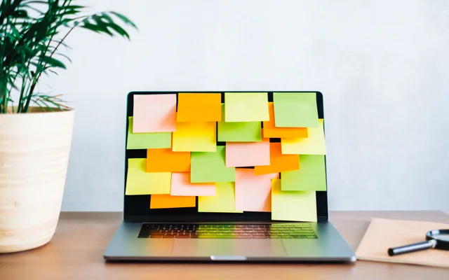 Post its på skærmen af en bærbar computer på et skrivebord